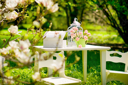 Photo: Table with chairs in a beautiful blooming garden Table with chairs in a beautiful blooming garden