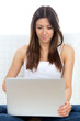 female sitting on a sofa with modern laptop typing on keyboard