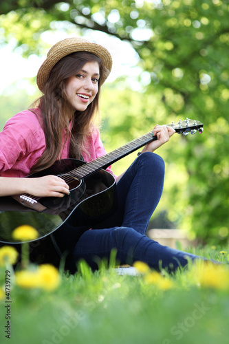 Foto: Woman playing guitar in park Woman playing guitar in park