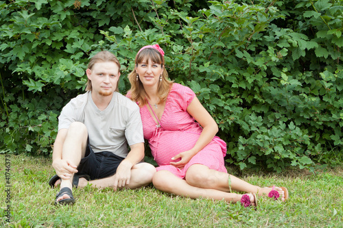 Photo: a happy young pregnant woman with her husband resting in a park a happy young pregnant woman with her husband resting in a park