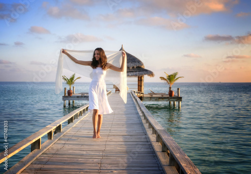 Foto: Sexy happy woman in white clothes standing on a jetty (Maldives) Sexy happy woman in white clothes standing on a jetty (Maldives)