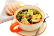 Fish soup with vegetables in bowl on a white background.