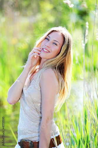 Photo: Beautiful blond woman standing in meadow with modern look Beautiful blond woman standing in meadow with modern look