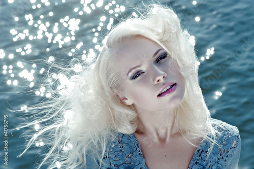 Photo: Portrait of beautiful young woman against water Portrait of beautiful young woman against water