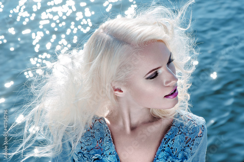 Photo: Portrait of beautiful young woman against water Portrait of beautiful young woman against water
