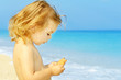Happy toddler girl holding her snack at the famous Egremni beach