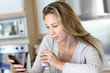 Young woman using smartphone at home with earphones