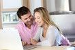 Happy couple websurfing on laptop computer at home