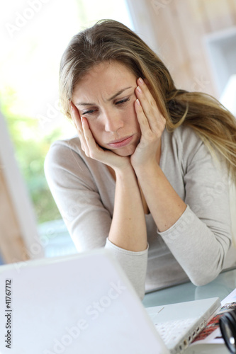 Photo: Active woman in front of laptop with upset look Active woman in front of laptop with upset look