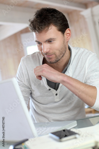 Photo: Man working at home on laptop computer Man working at home on laptop computer