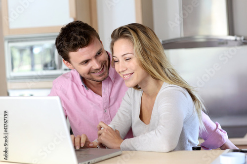 Photo: Happy couple websurfing on laptop computer at home Happy couple websurfing on laptop computer at home