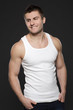 Young muscular man in white shirt standing with hands in pockets