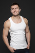 Young muscular man in white shirt standing with hands in pockets