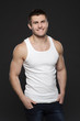 Young muscular man in white shirt posing with hands in pockets