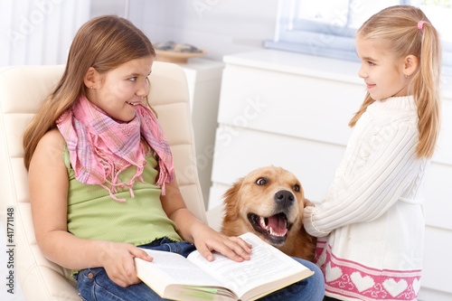 Photo: Little sisters with pet dog at home Little sisters with pet dog at home