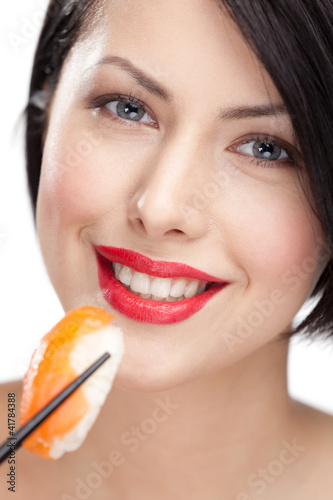 Photo: Young woman holding sushi with a chopsticks, closeup Young woman holding sushi with a chopsticks, closeup