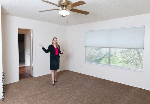 Photo: Young female real estate agent showing an empty home Young female real estate agent showing an empty home