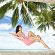 Happy woman relaxing in hammock on a tropical beach