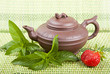 Ceramic tea, mint and strawberries on a green background