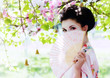Asian style portrait of young woman with fan in the garden