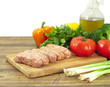 Raw sausages and fresh vegetables on a cutting board
