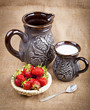 Strawberry, silver spoon and milk in a ceramic jug