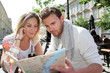 Couple sitting at a coffee shop terrace to look at map