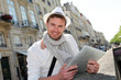 Young man with hat in town using electronic tablet Young man with hat in town using electronic tablet