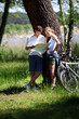 Couple on a bike ride making a stop to look at map Couple on a bike ride making a stop to look at map