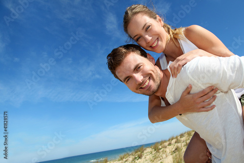 Foto: Man giving piggyback ride to girlfriend on a sand dune Man giving piggyback ride to girlfriend on a sand dune