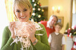 Photo: Woman holding illuminated Christmas tree lights, smiling, portrait, husband and son (9-11) in background. Woman holding illuminated Christmas tree lights, smiling, portrait, husband and son (9-11) in background.