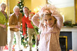 Girl (5-7) with Christmas lgihts on head, family in background, portrait