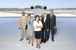 Photo: Small group of people in line behind woman by aeroplane on runway, portrait, elevated view Small group of people in line behind woman by aeroplane on runway, portrait, elevated view