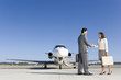 Photo: Businessman and woman with briefcase shaking hands by aeroplane on runway, low angle view Businessman and woman with briefcase shaking hands by aeroplane on runway, low angle view