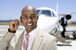 Photo: Businessman with hand on earpiece by man on stairs of aeroplane, smiling, portrait, close-up Businessman with hand on earpiece by man on stairs of aeroplane, smiling, portrait, close-up