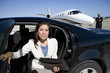Photo: Businesswoman with folder getting out of car on runway by aeroplane, smiling, portrait Businesswoman with folder getting out of car on runway by aeroplane, smiling, portrait