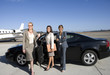Photo: Businesswoman with folder by open door of car on runway by aeroplane, flanked by colleagues, smiling, portrait Businesswoman with folder by open door of car on runway by aeroplane, flanked by colleagues, smiling, portrait