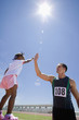 Photo: Male athlete giving girl (3-5) high five, low angle view (lens flare) Male athlete giving girl (3-5) high five, low angle view (lens flare)