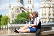 Romantic summer day in Paris, couple of tourists sitting by Notr