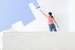 Woman painting living room wall with paint roller