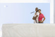 Photo: Smiling couple with paint roller standing next to freshly painted living room wall Smiling couple with paint roller standing next to freshly painted living room wall