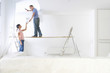 Woman handing coffee cup to man painting living room wall on wood plank