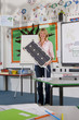 Foto: Smiling teacher holding solar panel in school classroom Smiling teacher holding solar panel in school classroom
