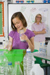 Smiling student putting glass into recycling bin