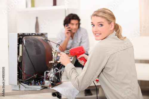 Photo: Woman repairing television with soldering iron Woman repairing television with soldering iron