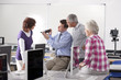Teacher talking to adult students studying in college evening class computer lab