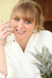 Smiling woman in bathrobe with glass of milk
