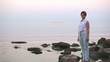 harmonous nice woman costs on the seashore and smiles