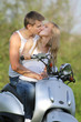 young loving couple on motorbike / scooter on natural background