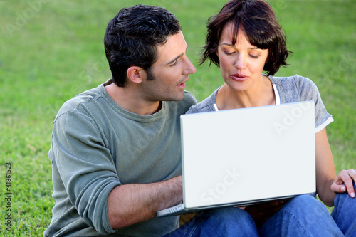 Photo: Couple making use of free wifi in the park Couple making use of free wifi in the park